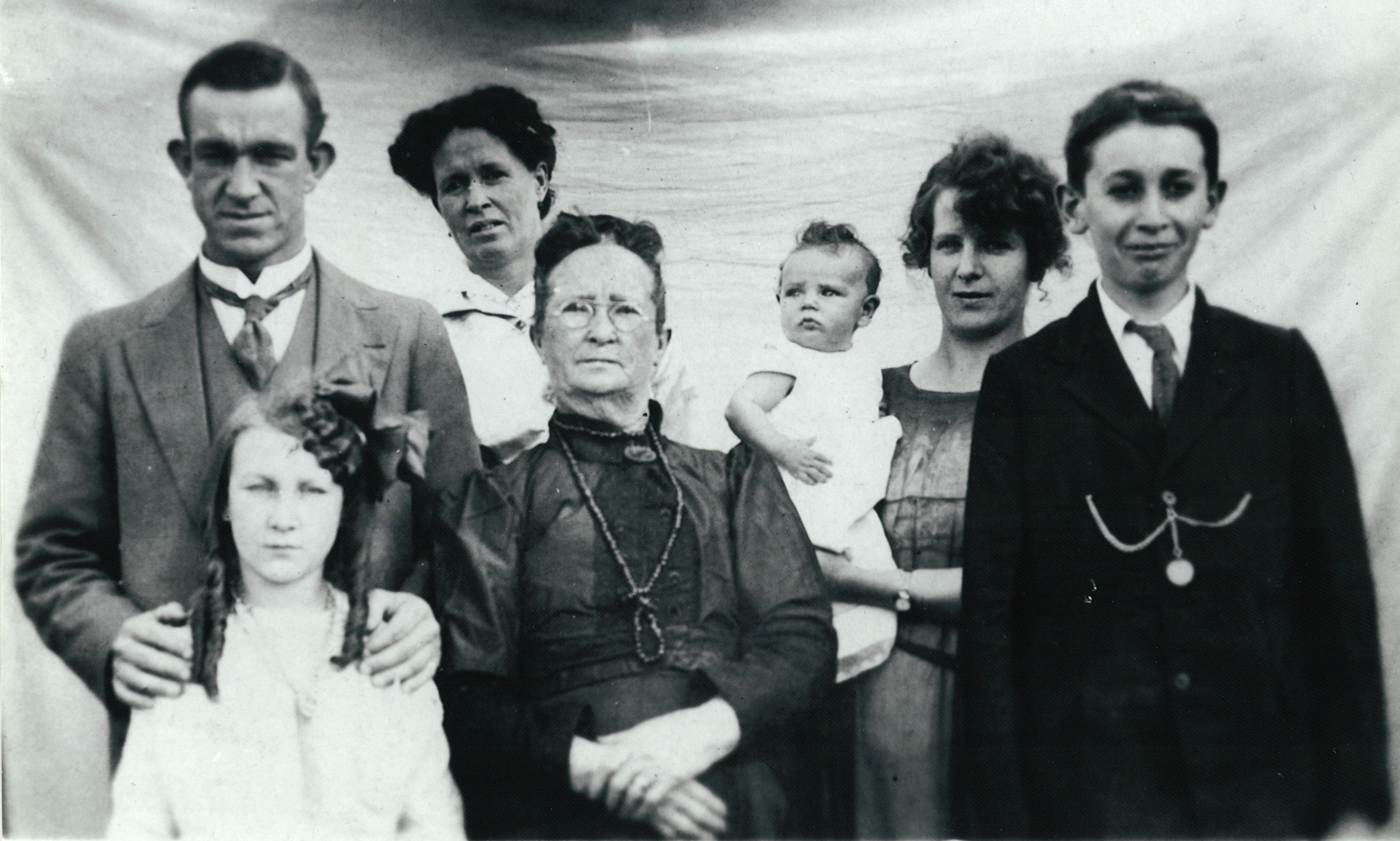 A black and white vintage photo of a family of seven, various ages and genders. 