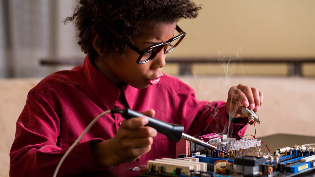 Young black boy is surprised whilst working on an electronic circuit