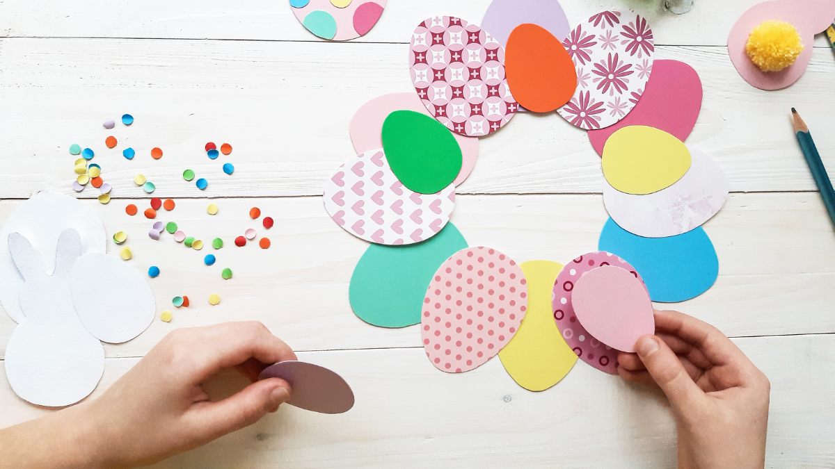 Child's hand creating easter themed craft with paper eggs